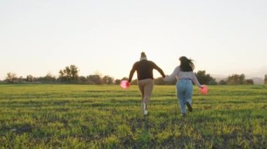 Happy couple run in the meadow to the sun.