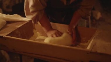 Hands of a lady kneading bread in the bowl.