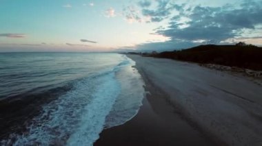 The rough ocean near the long sandy beach after a winter sunset