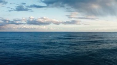 Ocean water with winter clouds in evening sky aerial view