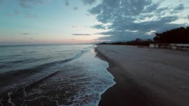 The rough ocean near the long sandy beach after a winter sunset