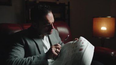 Ofiste elinde büyüteçle gazete okuyan bir iş adamı..
