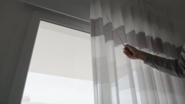 Evin perdelerini kapatan bir adamın eli..