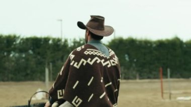 Çiftlikteki ata kovboy elbiseli bir adam biner..