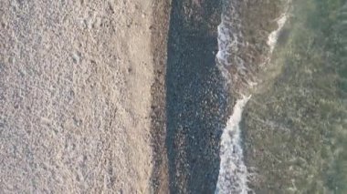 Yaz mevsiminde okyanus kıyısında sakin su dalgalarıyla bomboş bir sahil.