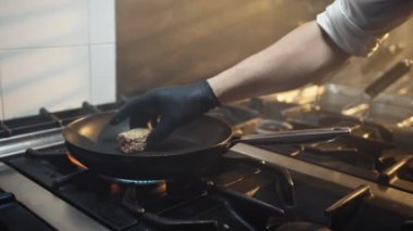 Şef bir restoranın mutfağında sıcak tavada balık pişiriyor.