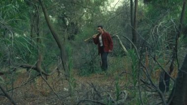Akşamları elinde satırla ormanda yürüyen korkmuş bir adam.