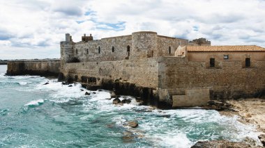 Dalgalar Syracuse 'daki Ortigia şatosunun kayalarında kırılıyor..