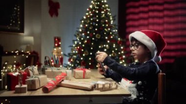 Küçük çocuk Noel ağacının altında akıllı telefondan yazı yazıyor. . 