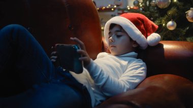 Noel şapkalı küçük çocuk video oyunları oynuyor. .