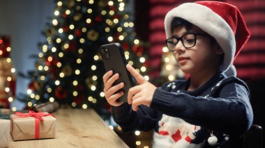 Çocuk Noel ağacını göstermek için akıllı telefonunu kullanıyor. .