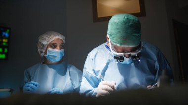 Diş hekimi cerrahi aletlerle diş çıkarıyor..