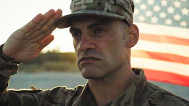 Üniformalı asker Amerikan bayrağının yanında hazır bekliyor..