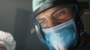 Doktor salgını önlemek için cerrahi yüz vizörü kullanıyor.