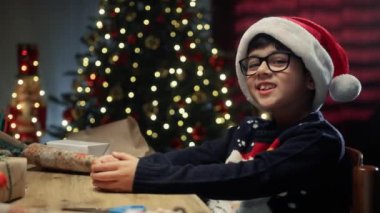 Genç çocuk Noel ağacının altında elleriyle kalp yapıyor. . 