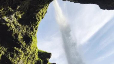 Bir mağaranın üstüne şelale düşüyor ve İzlanda 'da bazaltik kayalara çarpıyor..