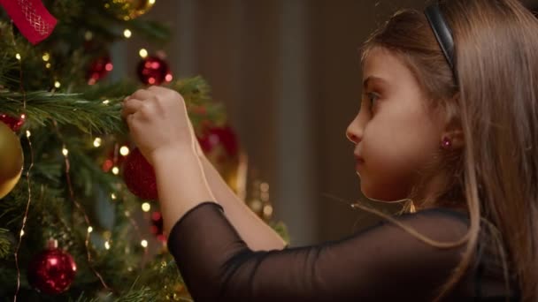 Niña Poniendo Una Bola Roja Para Decorar Árbol Navidad — Vídeo de stock