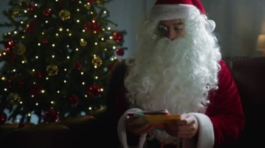 Noel ağacının altında Noel Baba çalışıyor ve mektuplar okuyor.. 