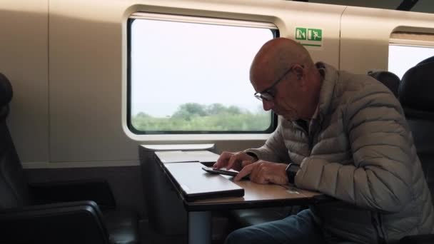 Vanha Mies Jolla Silmälasit Katselee Puhelintaan Matkustaessaan Junassa Italian Läpi — kuvapankkivideo