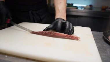 Şef bir restoranın mutfağına bıçakla kehribar balığı kesiyor..