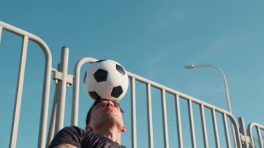 Çocuk kafasında futbol topuyla oynuyor..