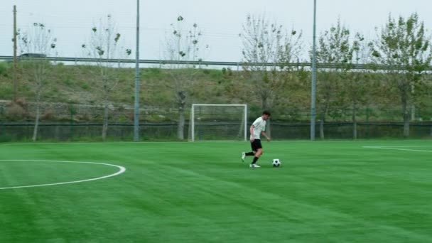 ティーンエイジャーサッカー選手はサッカーフィールドに合わせてボールで走ります — ストック動画