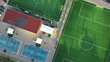 Oyuncuların oynadığı bir futbol sahasının havadan görüntüsü.