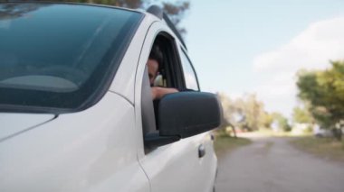 Beyaz arabalı çocuk pencereden dışarı bakar ve sevinir..