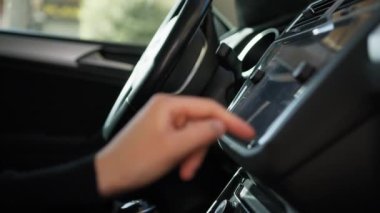Kadın arabasının torpidosundaki düğmelere basıyor..