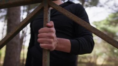 Siyah eşofman giymiş bir adamın eli korkuluklara yanaşıyor..