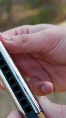 Delikanlı açık havada Mızıka ile Müzik Çalıyor.