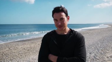 Adam sahilin kenarında mutlu bir şekilde gülümsüyor..