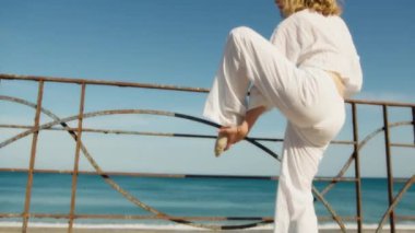 Yazın plajda beyazlar içinde dans eden genç bir kadın.