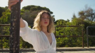 Yazın plajda beyazlar içinde dans eden genç bir kadın.