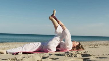 Yazın plajda beyazlar içinde dans eden genç bir kadın.