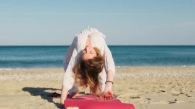 Yazın plajda beyazlar içinde dans eden genç bir kadın.