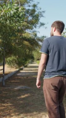 Adam parkta yürürken telefonla konuşuyor..