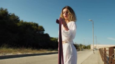 Yazın plajda beyazlar içinde dans eden genç bir kadın.