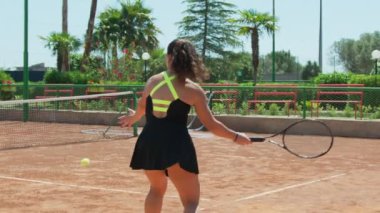 Bayan eğitmen, gündüz vakti Clay Court 'ta tenis öğretiyor..