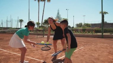 Bayan eğitmen, gündüz vakti Clay Court 'ta tenis öğretiyor..