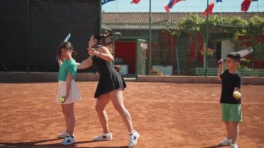 Bayan eğitmen, gündüz vakti Clay Court 'ta tenis öğretiyor..