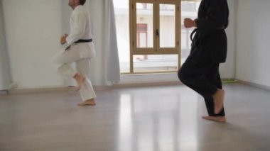 İki sporcu kapalı odada karate egzersizi yapıyor..