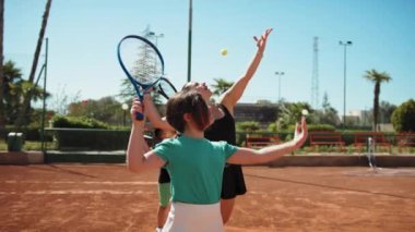 Bayan eğitmen, gündüz vakti Clay Court 'ta tenis öğretiyor..