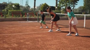 Bayan eğitmen, gündüz vakti Clay Court 'ta tenis öğretiyor..