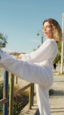 Yazın plajda beyazlar içinde dans eden genç bir kadın.