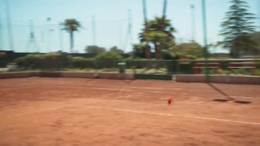 Bayan eğitmen, gündüz vakti Clay Court 'ta tenis öğretiyor..