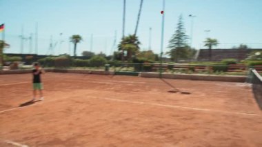 Bayan eğitmen, gündüz vakti Clay Court 'ta tenis öğretiyor..