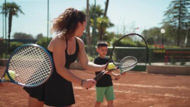 Bayan eğitmen, gündüz vakti Clay Court 'ta tenis öğretiyor..