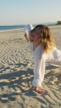 Yazın plajda beyazlar içinde dans eden genç bir kadın.