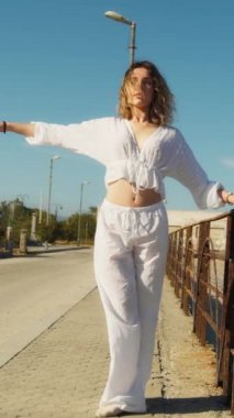 Yazın plajda beyazlar içinde dans eden genç bir kadın.